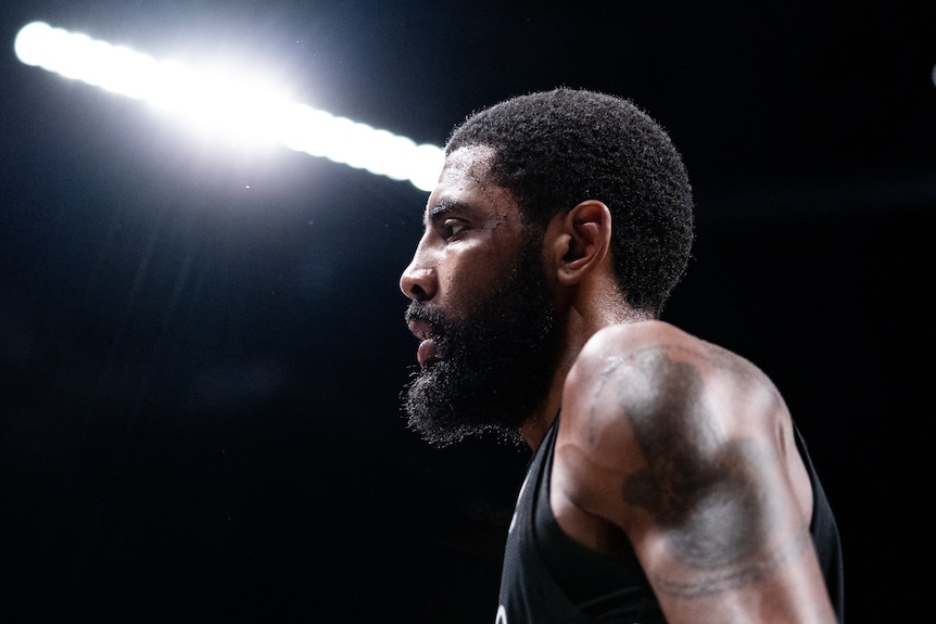 Kyrie Irving on a basketball court under bright lights.
