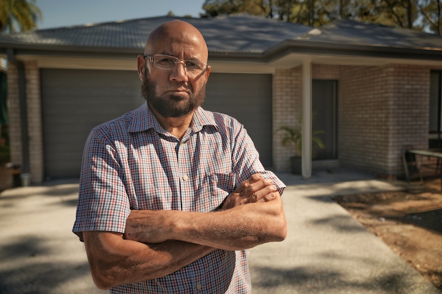 Mian Waqr pictured with his arms crossed standing outside his house. 