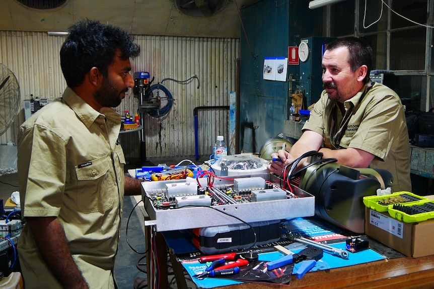 Two men talking in a workshop 