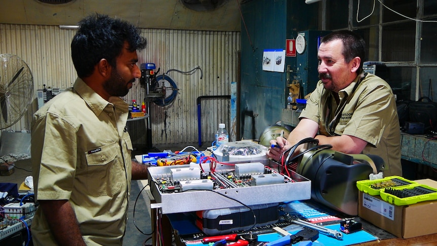 Two men talking in a workshop 