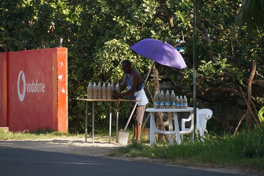 A vendor sells bottles of kava at a stall on a road outside Port Vila, Vanuatu.
