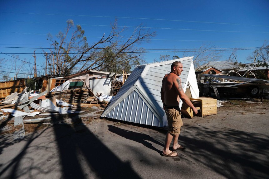 A shirtless man walks past debris in the town of Panama City