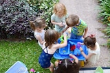 Children cluster around a water table.
