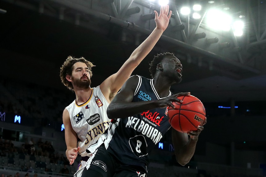 Basketballer drives to the basket during a match with a defender behind him