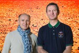 Two men stand in front of a photograph of the the Mars landscape.