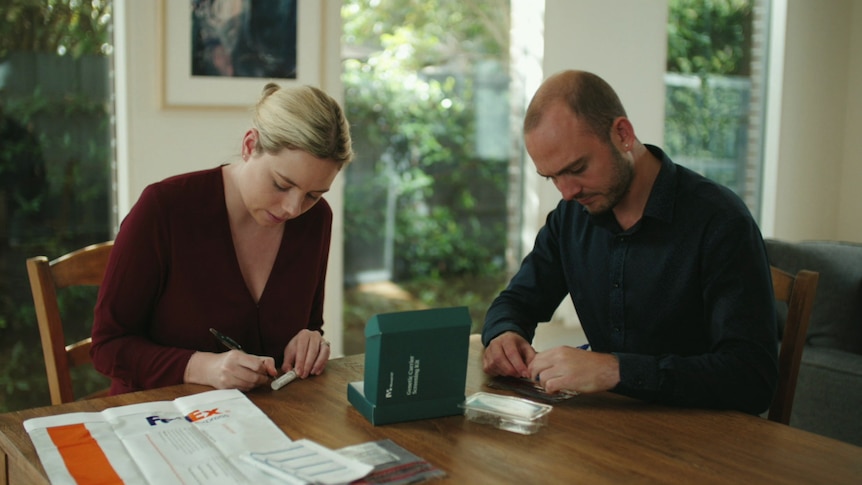 a couple are dealing with a pair of test tubes at a table in their home, they're probably looking to complete a genetic test