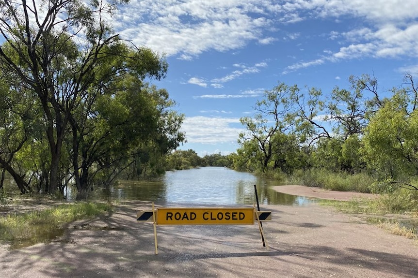 A flooded road with a sign.