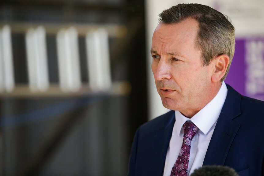 A close up of Mark McGowan wearing a suit and a purple tie while addressing media