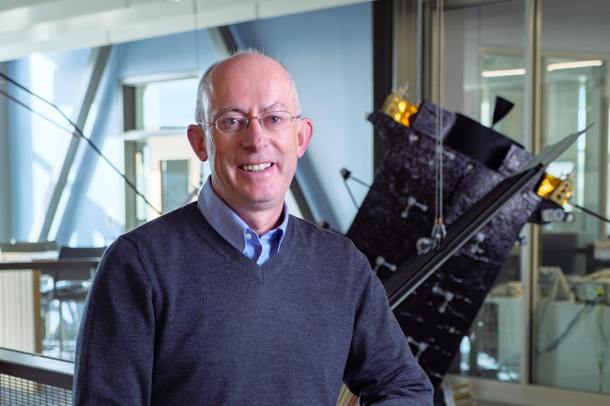 Professor stands in front of aircraft machinery.