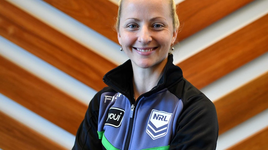 A female NRL referee looks straight at the camera while smiling and having her arms crossed.