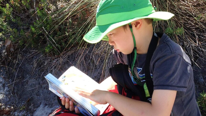 Budding ornithologist 10-year-old Austin McConville from Melbourne looking up a species in his bird book