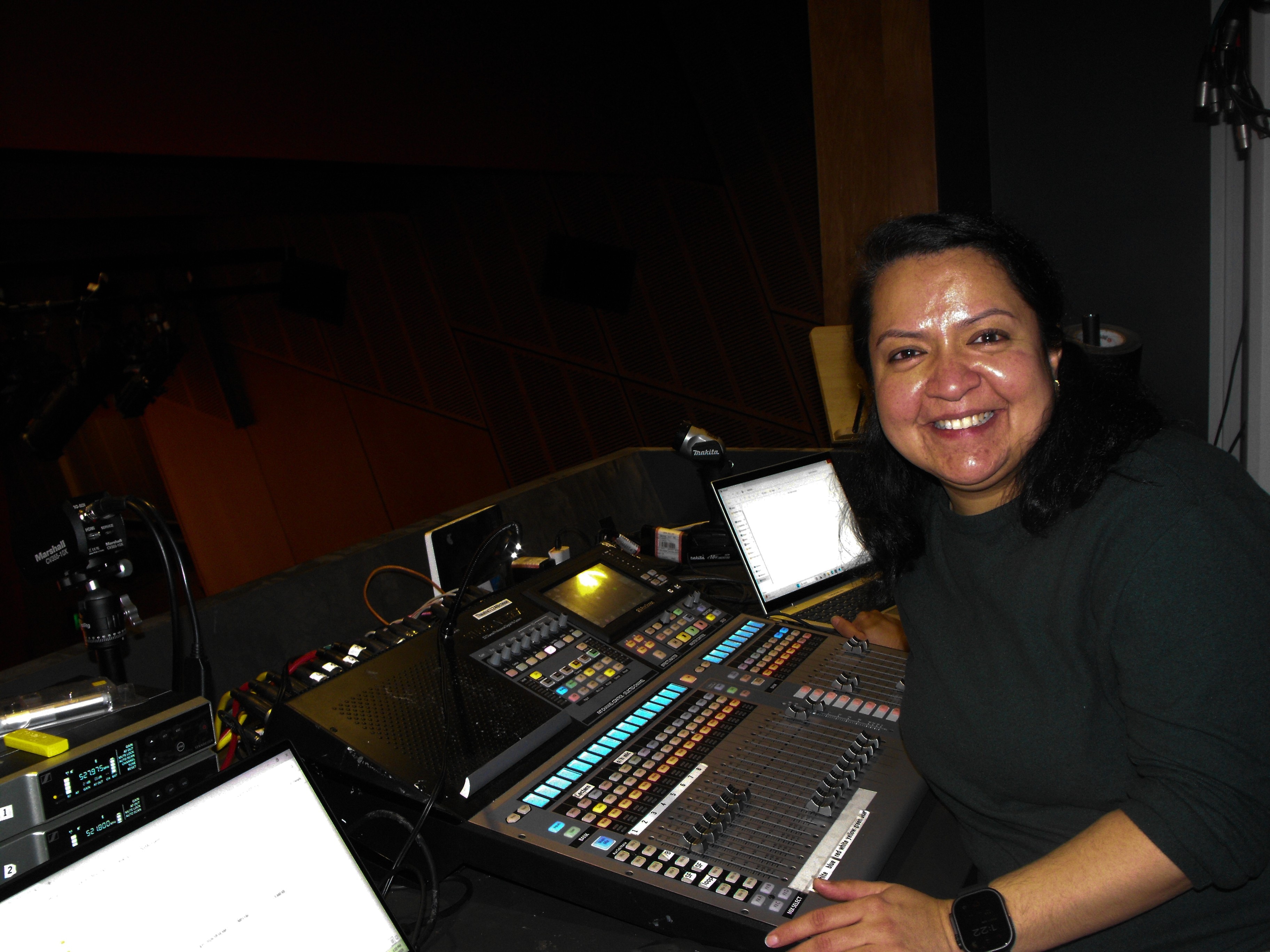 Sunyana sits in front of a console, smiles at the camera.