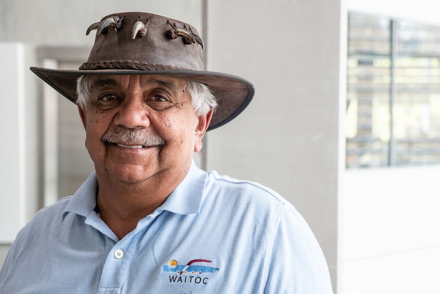A close up of a man in an Akubra hat smiling at the camera