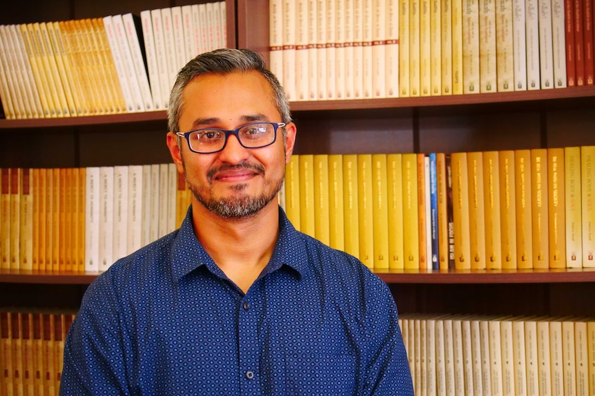 Muslim man standing in front of bookcase