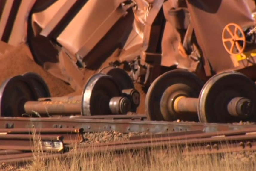 Axles from an iron ore train lie on the ground near other wreckage.