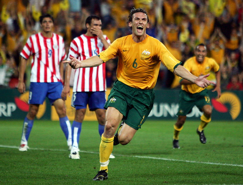Tony Popovic in green and gold runs and celebrates.