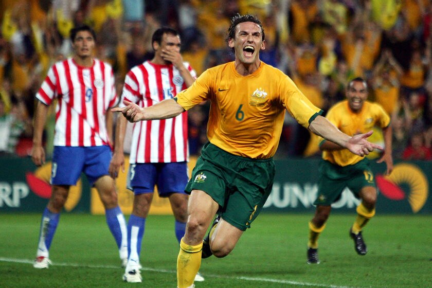Tony Popovic celebrates scoring a goal for Australia against Paraguay with his arms outstretched.