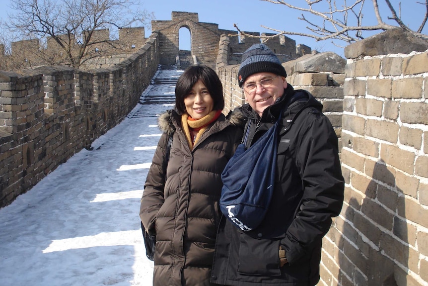 Yu Yingzeng and Peter Humphrey stand on the Great Wall of China and smile at the camera.