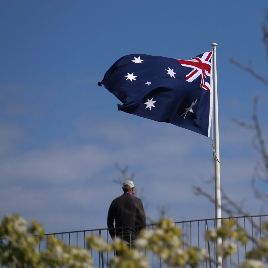 A man stands in front of the Australian flag.