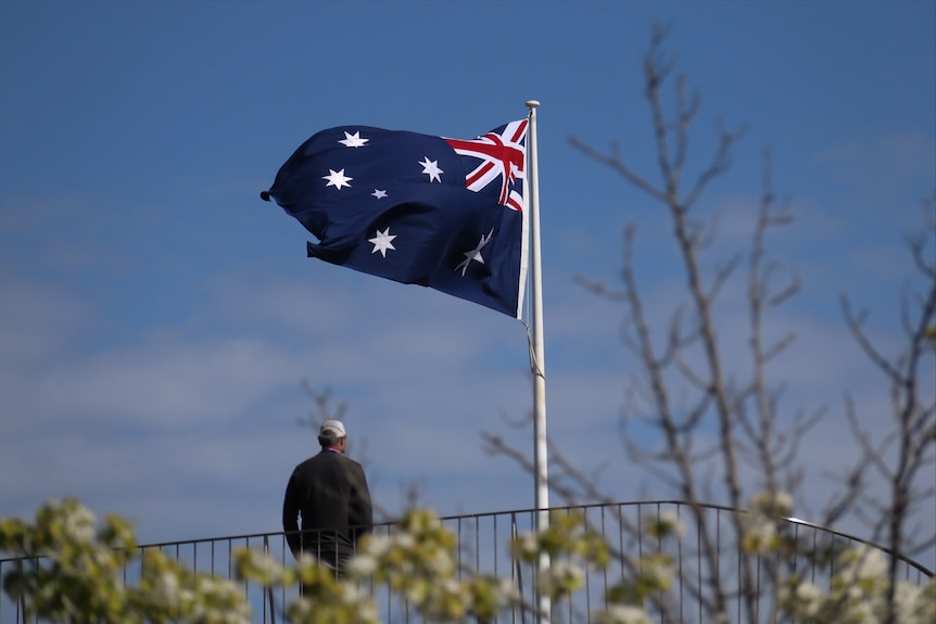 A man stands in front of the Australian flag.