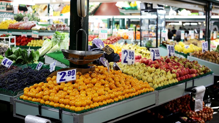 Mandarins are advertised for $2.99/kg at a fresh fruit and vegetable stall in the market.