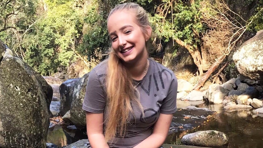 Larissa Beilby sitting on a rock beside a river