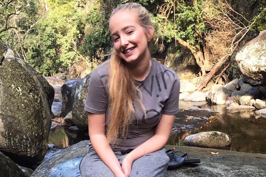 Larissa Beilby sitting on a rock beside a river
