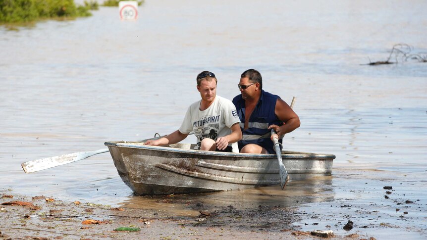 Residents are ferried from their property by neighbours in Waterford, south of Brisbane on Saturday afternoon.