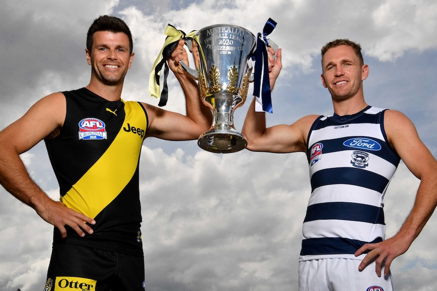 Richmond's Trent Cotchin and Geelong's Joel Selwood smile while holding up the AFL premiership cup from either side