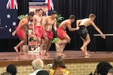 A group of people dancing on stage as other students look on.