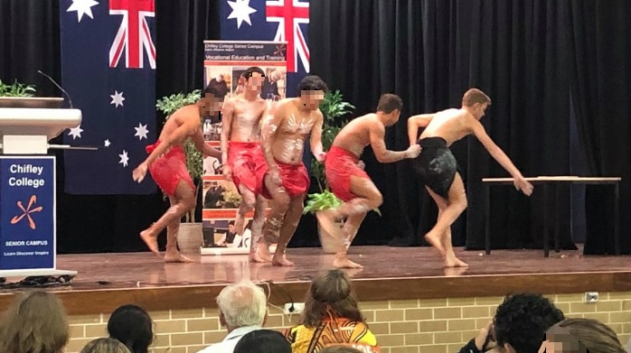 A group of people dancing on stage as other students look on.