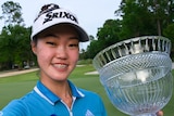 Grace Kim smiles for a selfie while holding the IOA Golf Classic trophy in Florida