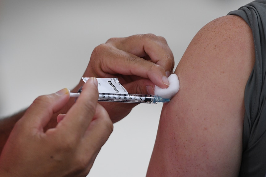 A vaccination needle is inserted into a person's upper arm.