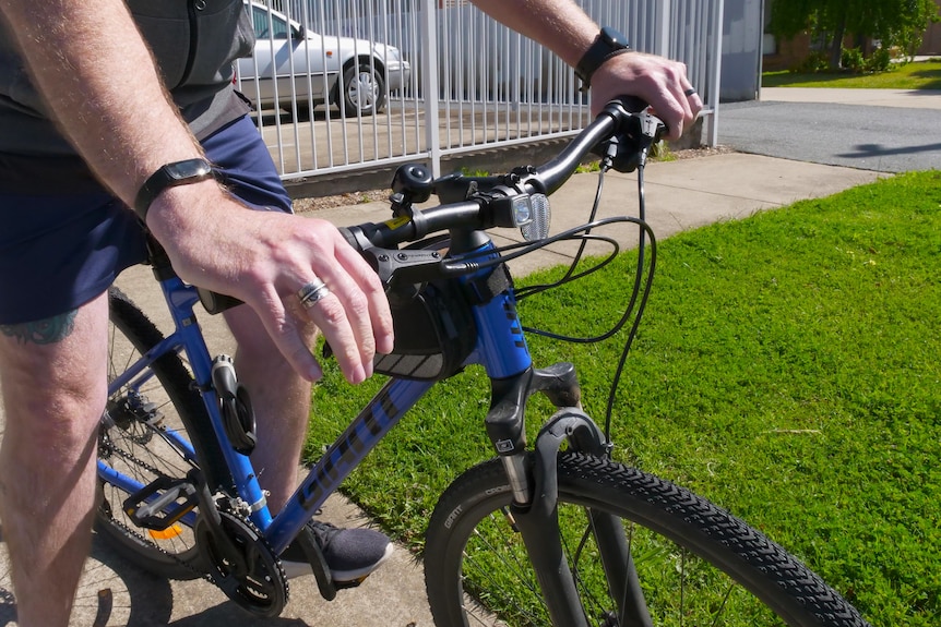 A man sitting on a bike and holding the handlebars.