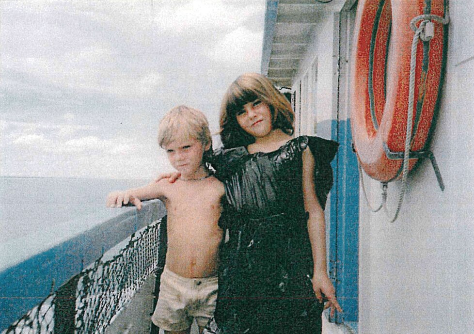 A young girl and a young boy pose for photo on a boat