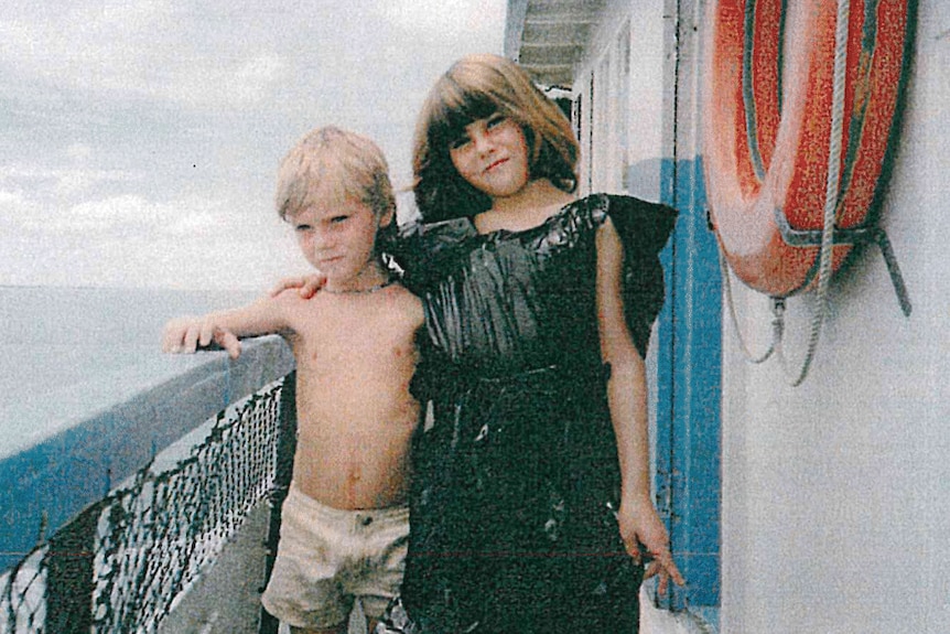 A young girl and a young boy pose for photo on a boat
