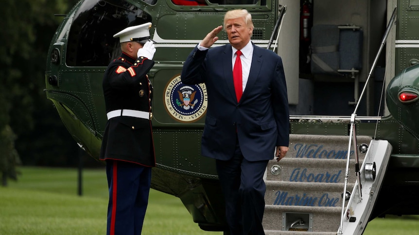 Trump salutes a marine as he leaves the presidential helicopter.