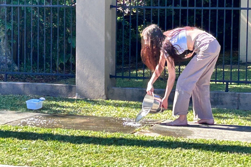 A young woman washes blood off a public footpath