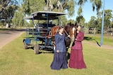 Two women dressed in period costume in front of a horse and carriage