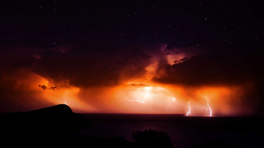 Lightning creates a visible glow over Bald Head rocks in Torndirrup National Park.