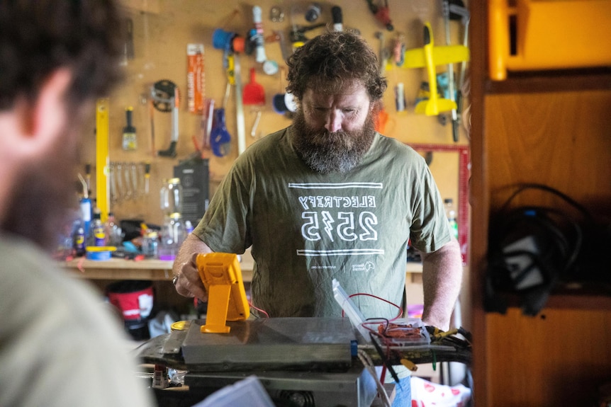 Man works on an electric invention in his workshop.