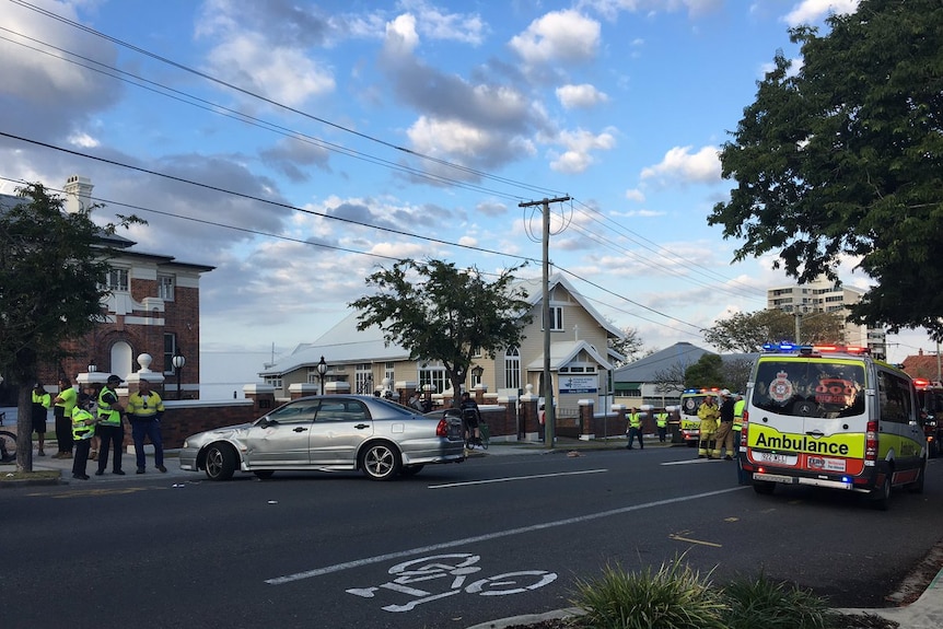 An ambulance sits in the street with paramedics nearby