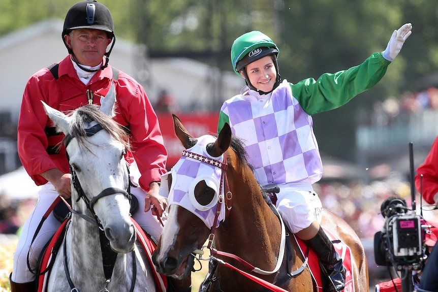 Michelle Payne waves to the crowd as she returns on Prince Of Penzance after winning the Melbourne Cup.