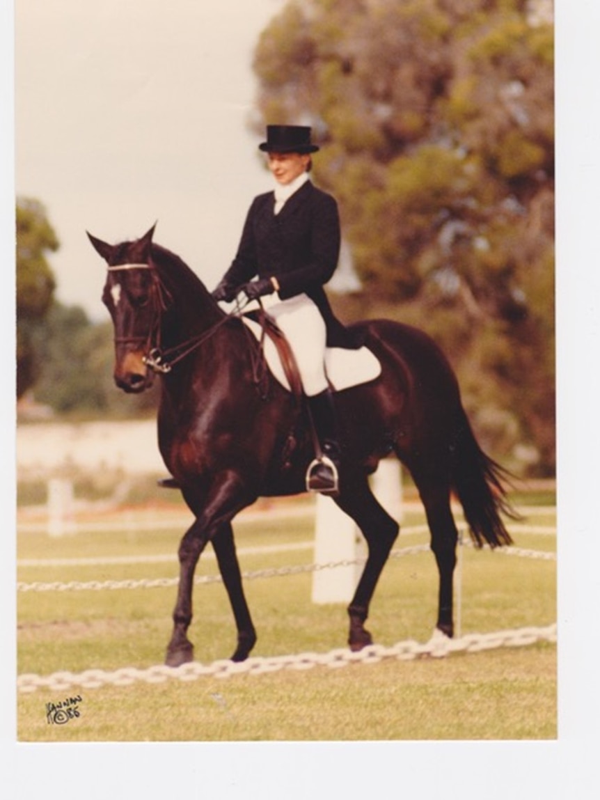 Woman in formal riding clothes riding black/brown horse in dressage arena