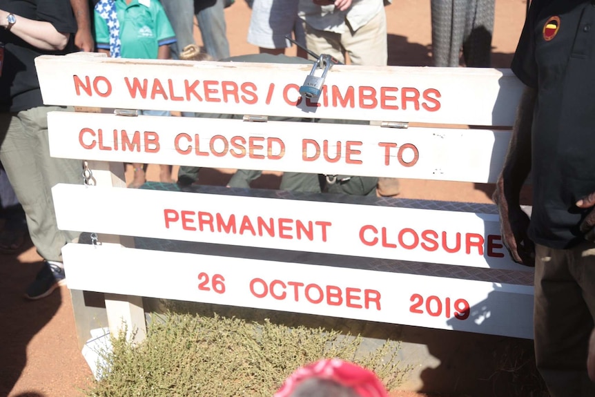 A sign at the base of Uluru reads "No walkers climbers climb closed due to permanent closure 26 October 2019".