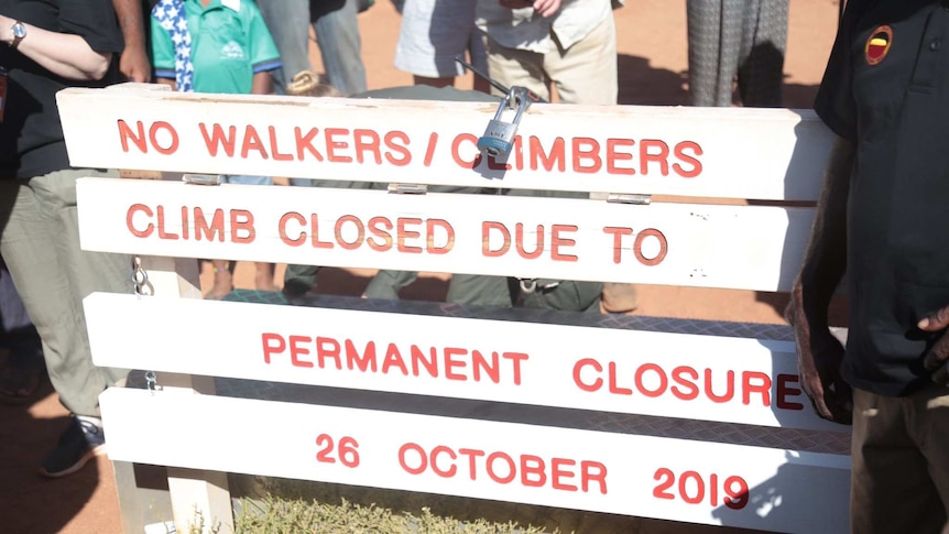 A sign at the base of Uluru reads "No walkers climbers climb closed due to permanent closure 26 October 2019".