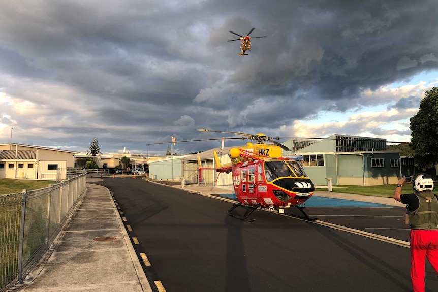 A helicopter prepares to take off while another flies above, on their way to help rescue efforts after a volcano eruption.