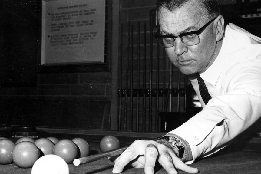 A man wearing a tie and glasses lines up a shot on a pool table.