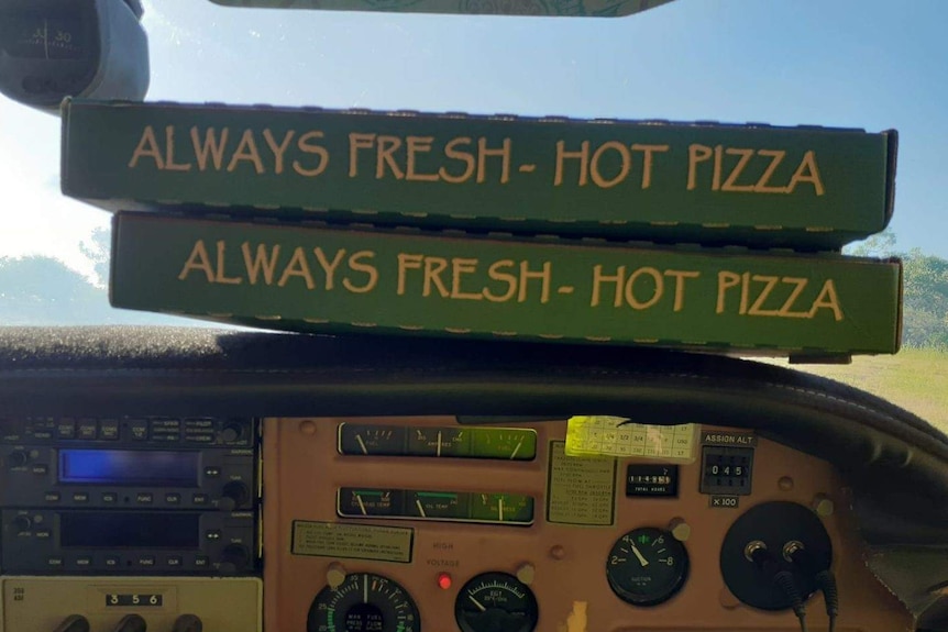 Pizza boxes resting on the dash of a light plane near Dunmarra roadhouse