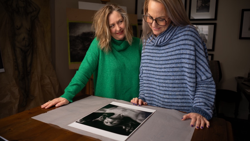 An older woman in her 40s and a young teenage girl smile and pose for the camera.